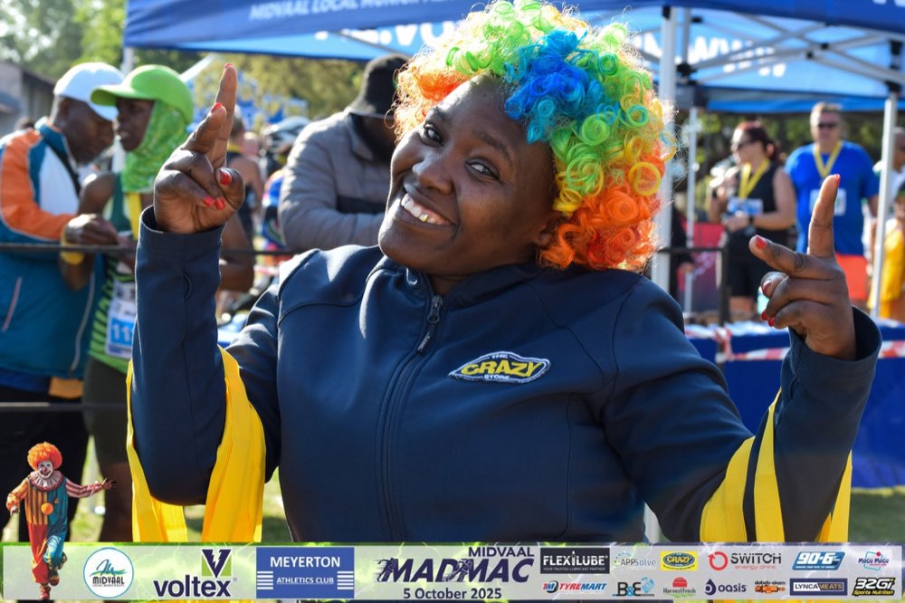 A Crazy Store volunteer in a rainbow wig celebrating at the finish area