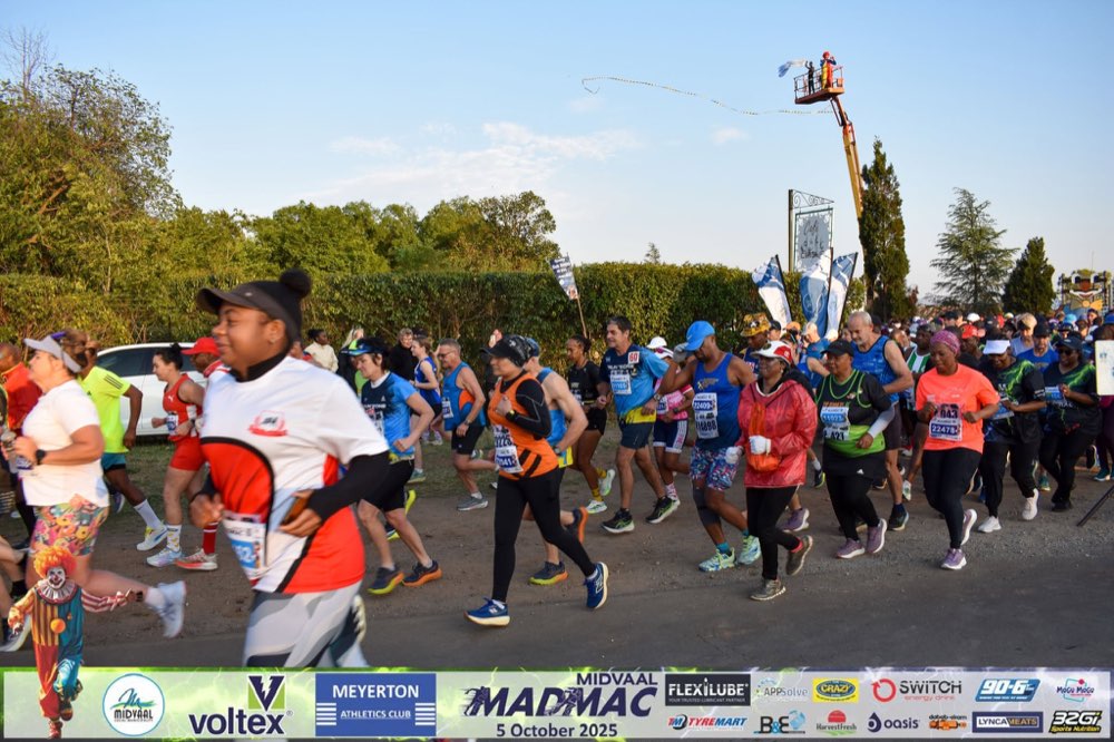 MadMac finishers running together, one wearing festive wigs, near the finish