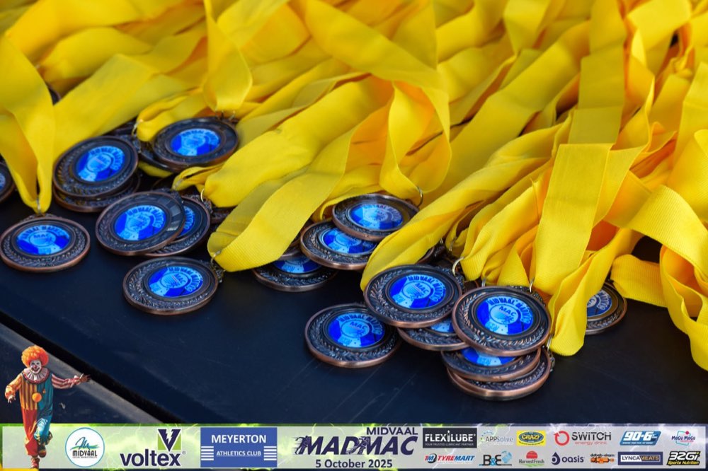 A pile of MadMac finisher medals on blue and yellow ribbons
